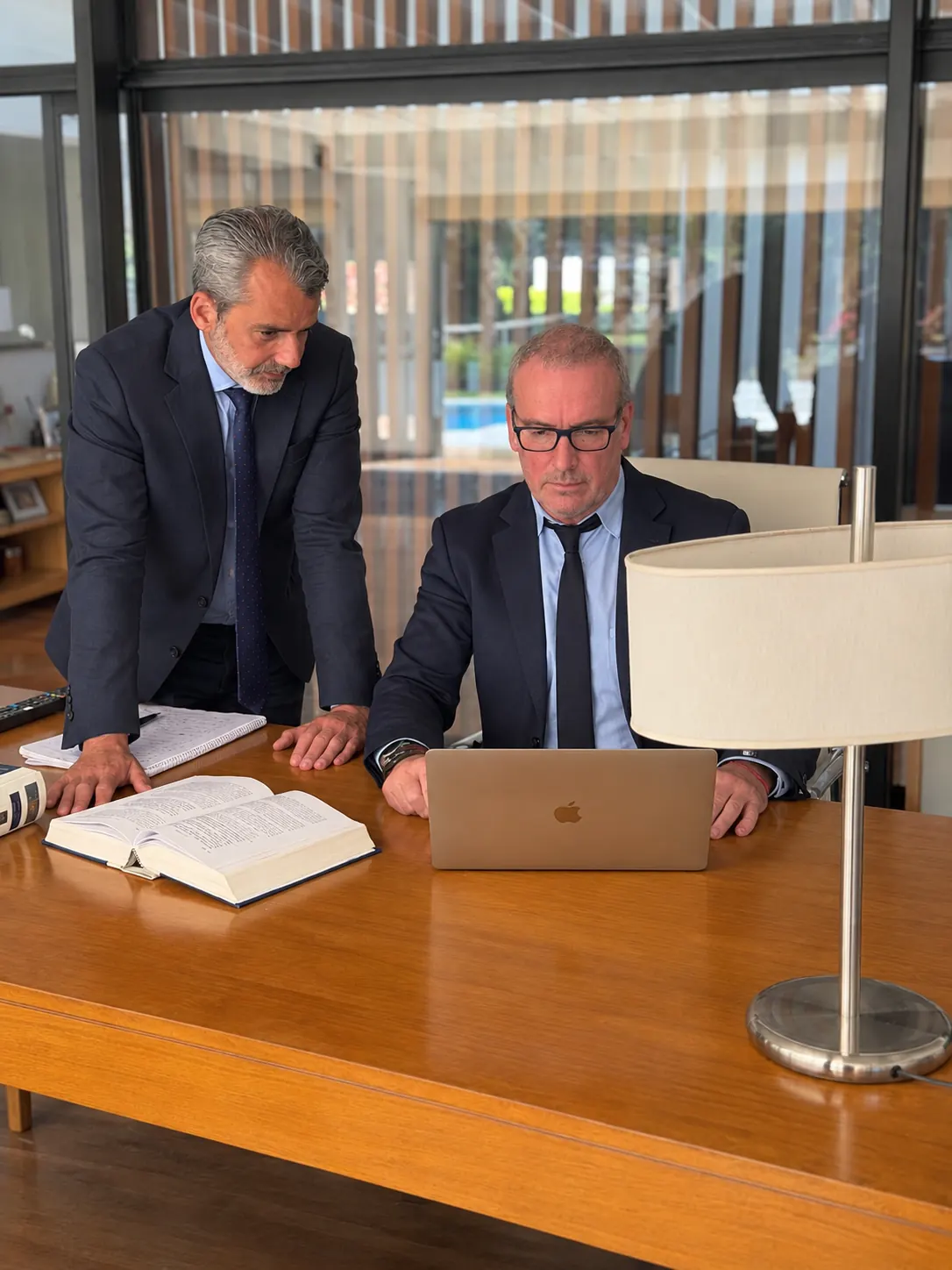 Sebastián Saborido, de pie, y Juan José Ross revisan un expediente en el escritorio del estudio.